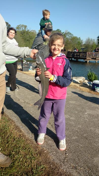 Young girl holding fish  with people around her