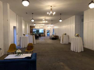 A spacious room featuring multiple tables and chairs, adorned with elegant chandeliers hanging from the ceiling.