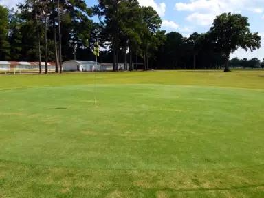 golf course with trees and a white building in the background